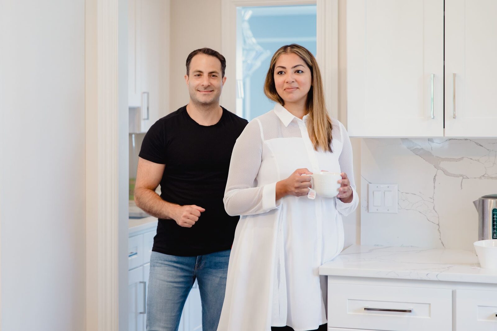 A couple enjoying a modern kitchen, engaging with each other in a bright, relaxed atmosphere.