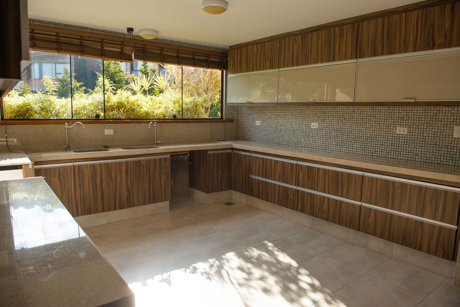 A spacious modern kitchen with wood cabinetry and large windows inviting ample sunlight.